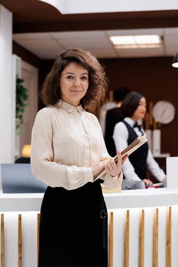 Woman standing at a hotel reception desk holding a folder
