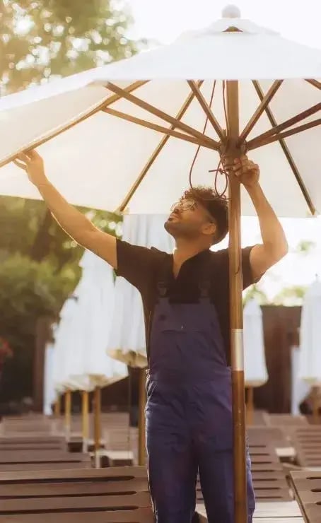 Worker setting up a large outdoor umbrella